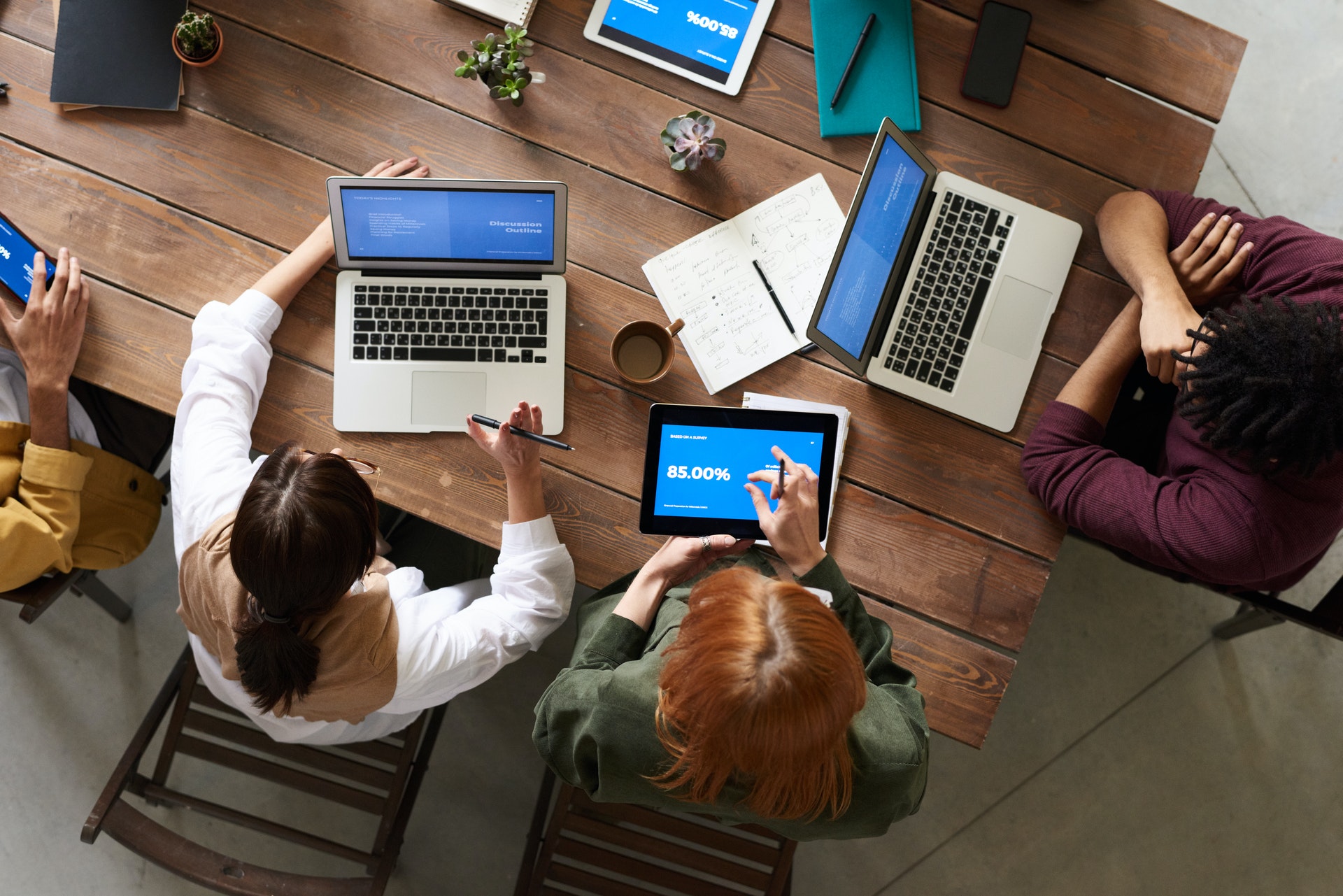 an overhead view of a business meeting with people on their laptops and tablets